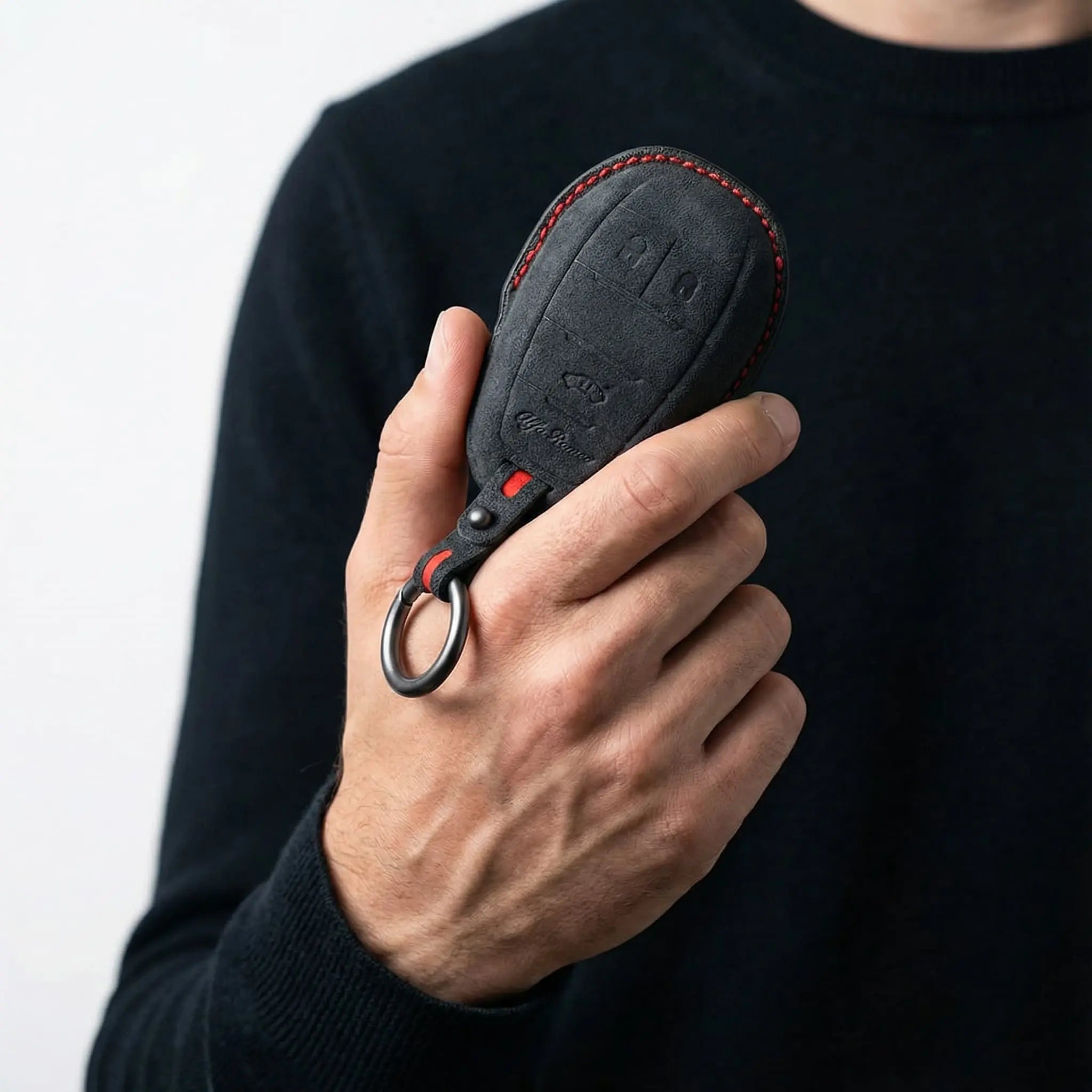 Hand holding Alfa Romeo Alcantara key cover dark grey with red stitching - Giulia Stelvio key fob