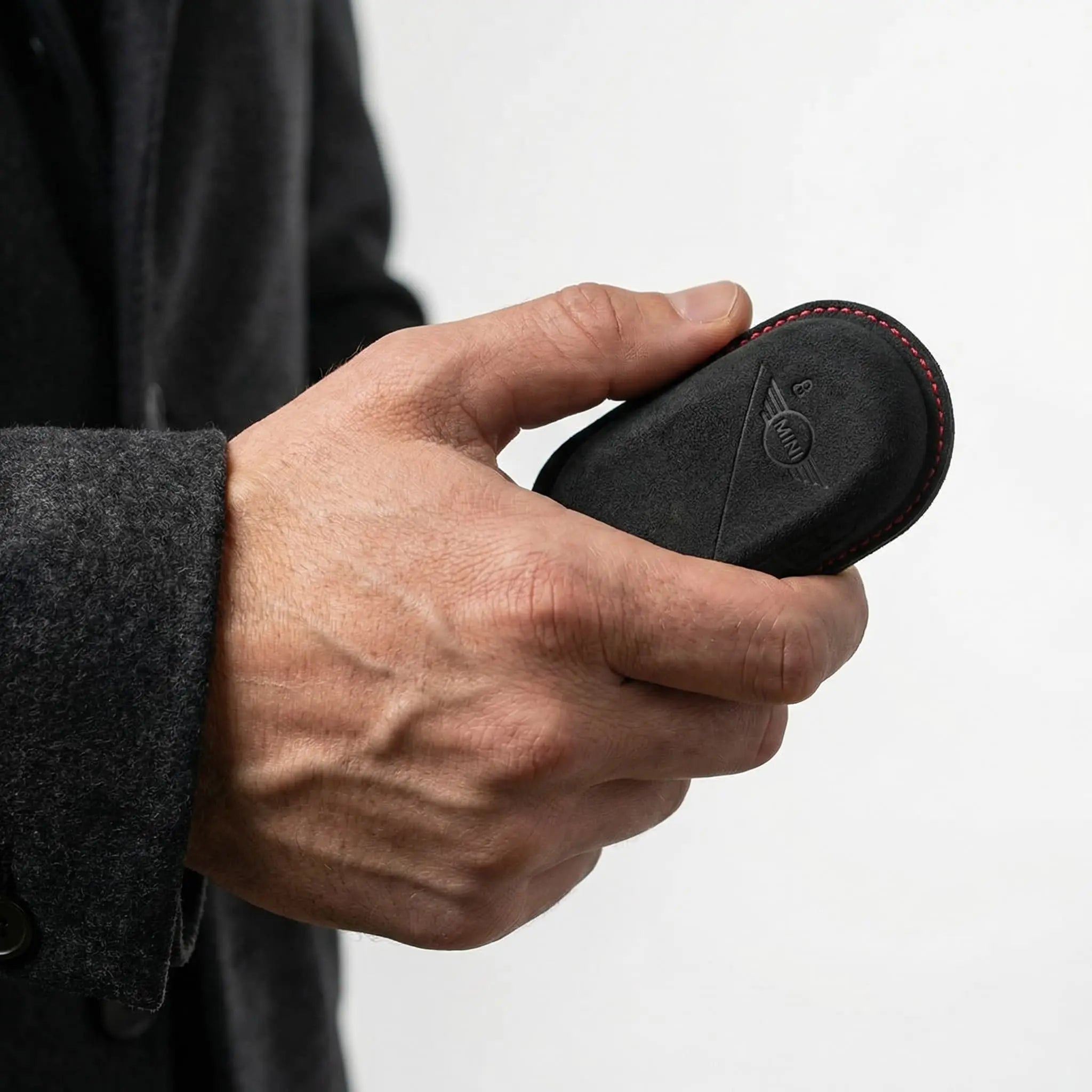 Hand holding Mini Cooper Alcantara key cover dark grey with red stitching - suede key fob protection
