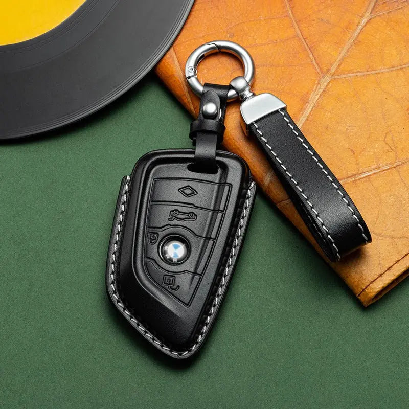 BMW key in a black leather key cover on a green and orange background