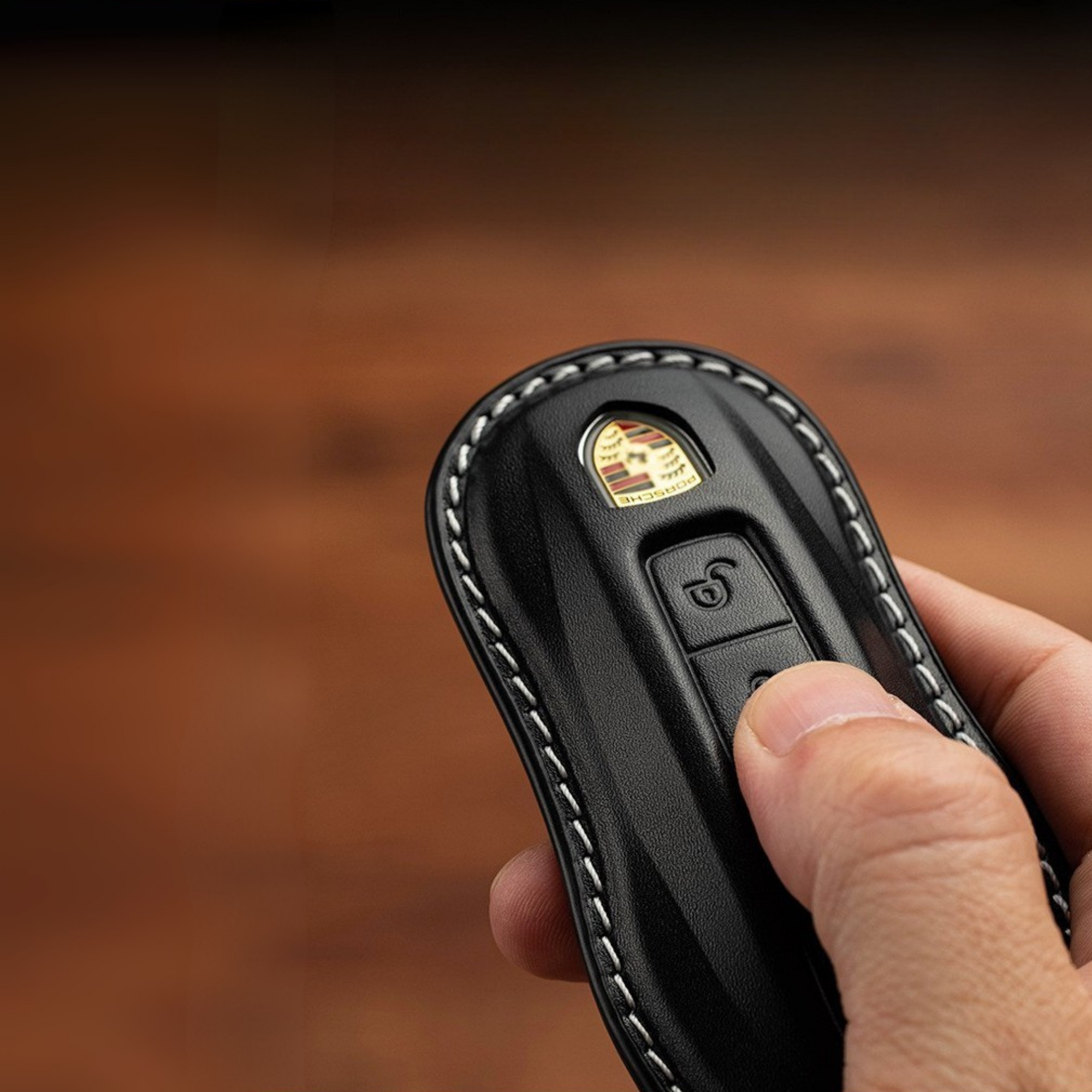 Close-up of hand holding Porsche key in leather sleeve