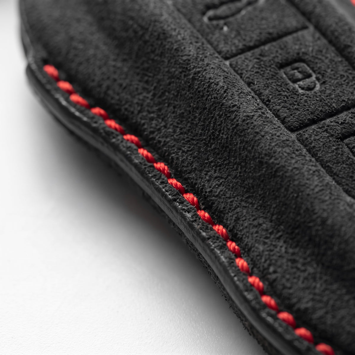 Close-up of red hand stitching and Alcantara suede texture on the Porsche key cover