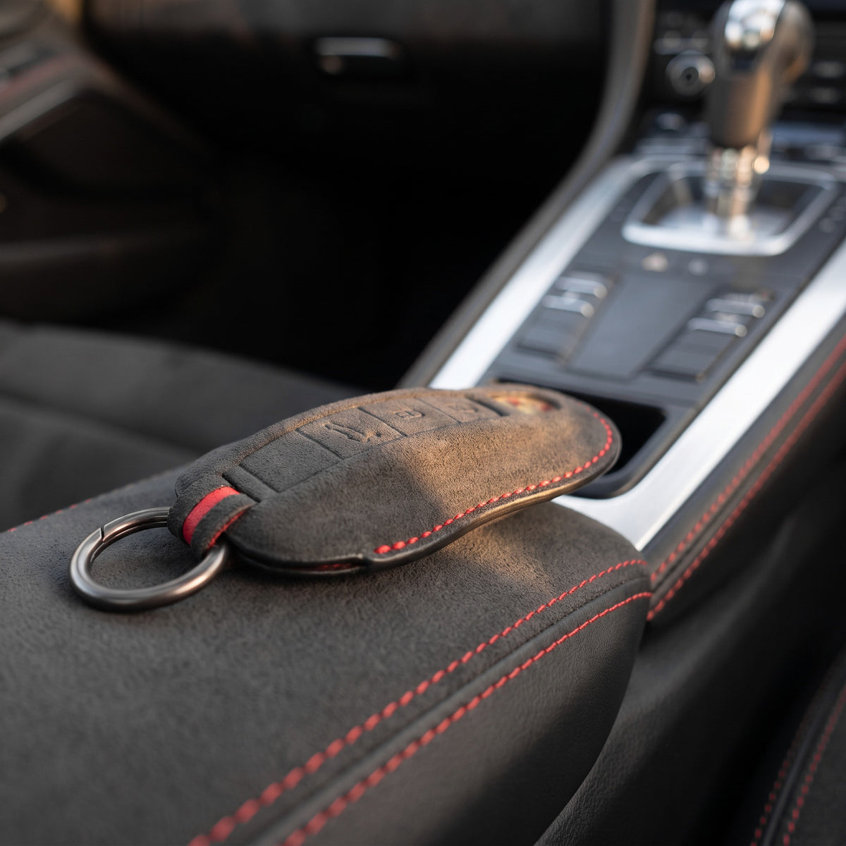 Alcantara Porsche key cover with red stitching on the centre console of a car