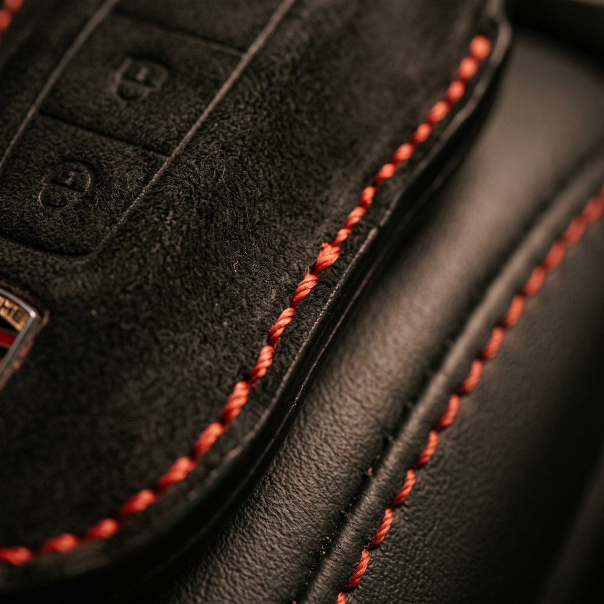 Macro of red contrast hand-stitching on a suede key cover